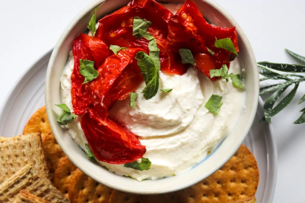 overhead view of roasted red peppers on top of whipped feta dip