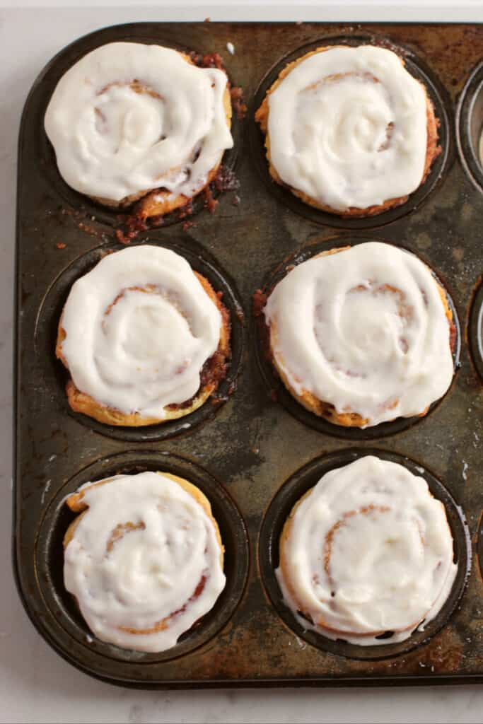cinnamon rolls with icing on them in a muffin tin