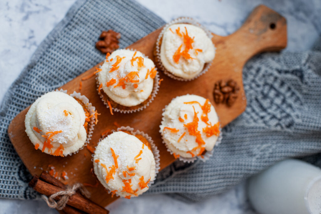 overhead shot of carrot cake cupcakes on a wooden board