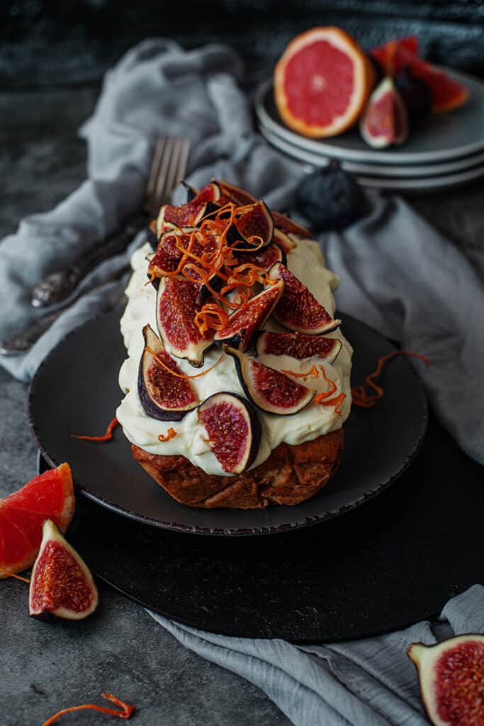 overhead shot of a iced fig bread cake recipe on a dark grey plate with blood oranges