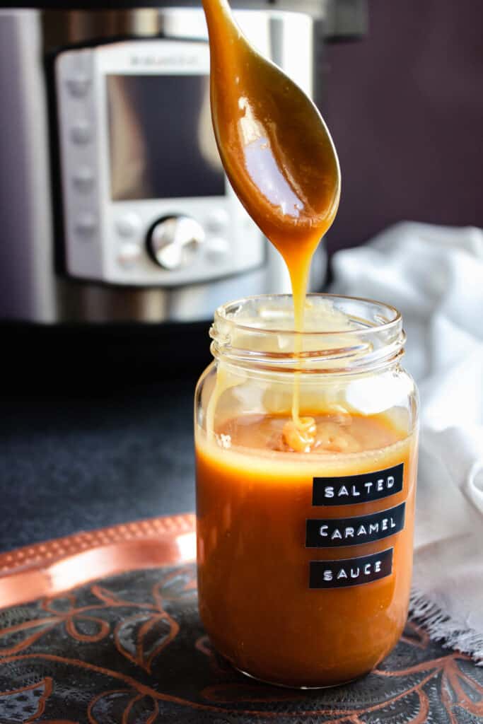 instant pot salted caramel sauce drizzling off a teaspoon