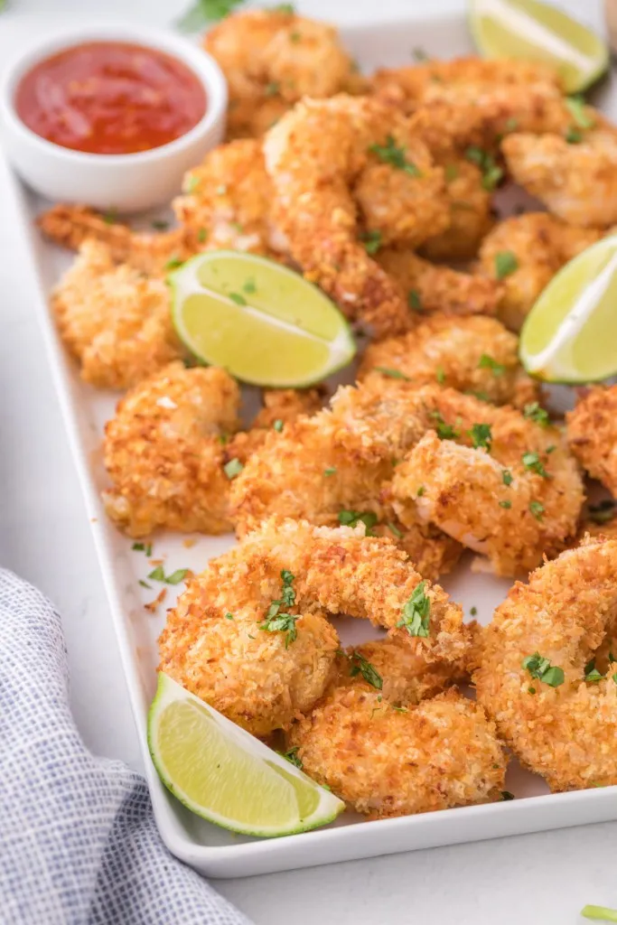 air fryer coconut shrimp with lime wedges on a sheet tray