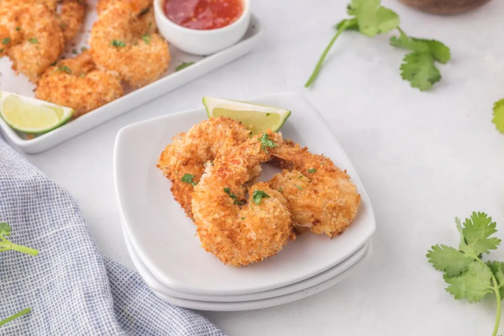 coconut shrimp with lime wedges on white plates made in the air fryer