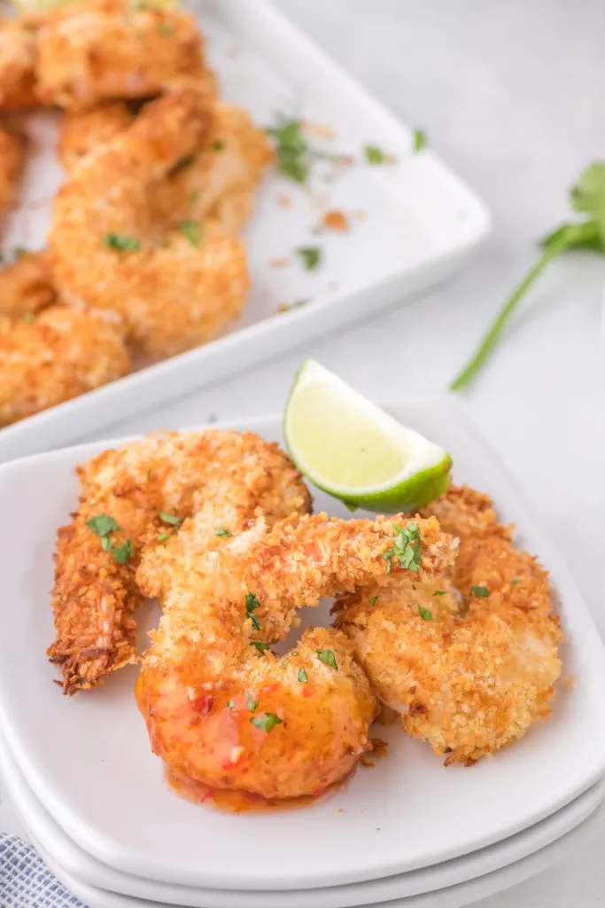 coconut shrimp on white plates with lime wedge