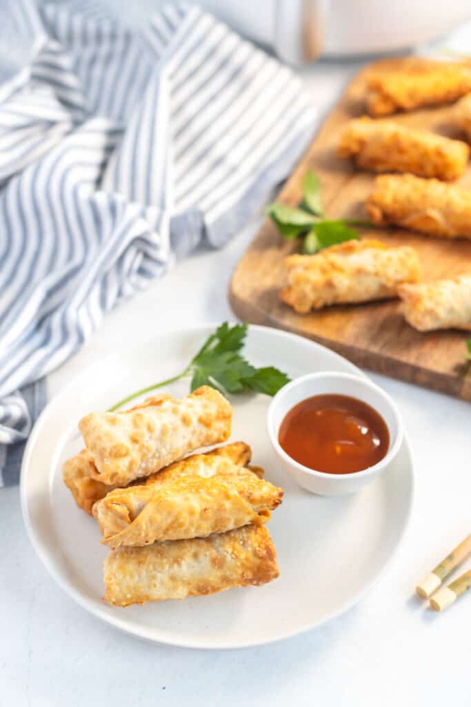 overhead shot of egg rolls made in the air fryer on a white plate with a blue striped napkin