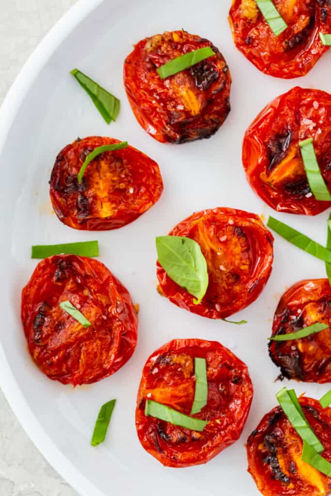 close up view of roasted tomatoes made in an air fryer on a white plate