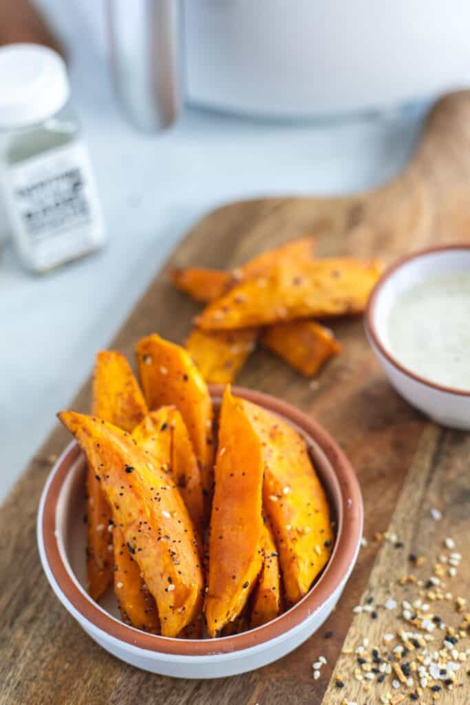 close up view of air fryer sweet potato wedges in a white while with a brown lip