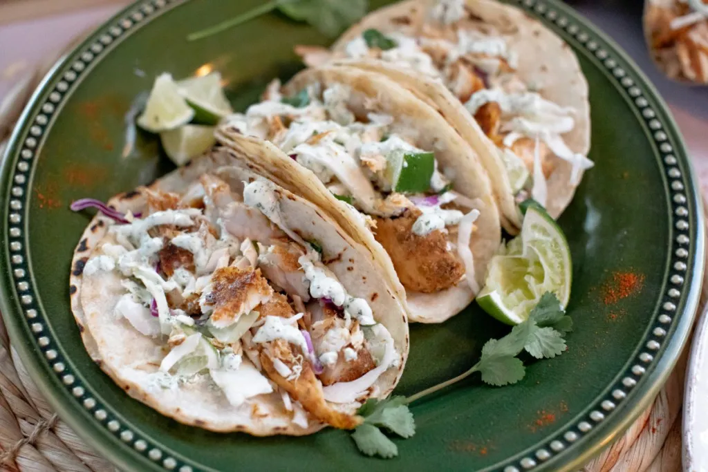 overhead shot of blackened mahi mahi fish tacos on a green plate with cilantro