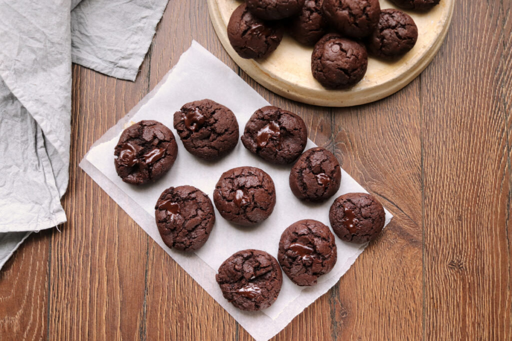 double chocolate cookies on parchment paper and wood background