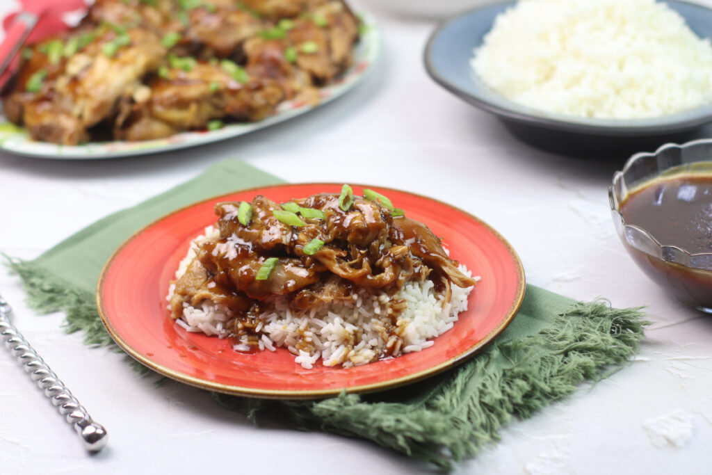 side view of instant pot adobo chicken on a red plate and green napkin