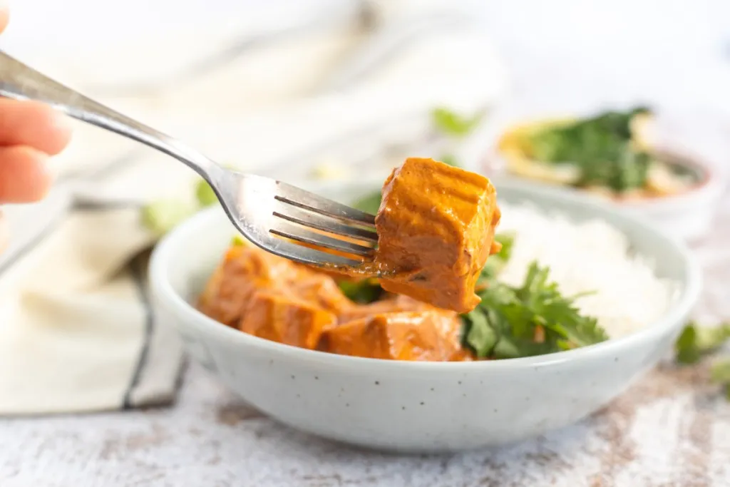 tofu curry on a fork in a white bowl