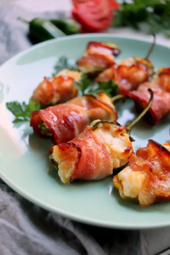 keto bacon wrapped jalapenos on a blue plate with a gray napkin