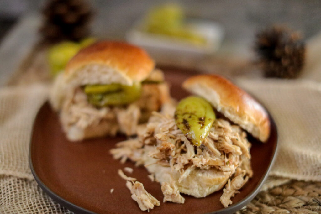 overhead shot of mississippi chicken sliders with one open faced on a brown plate