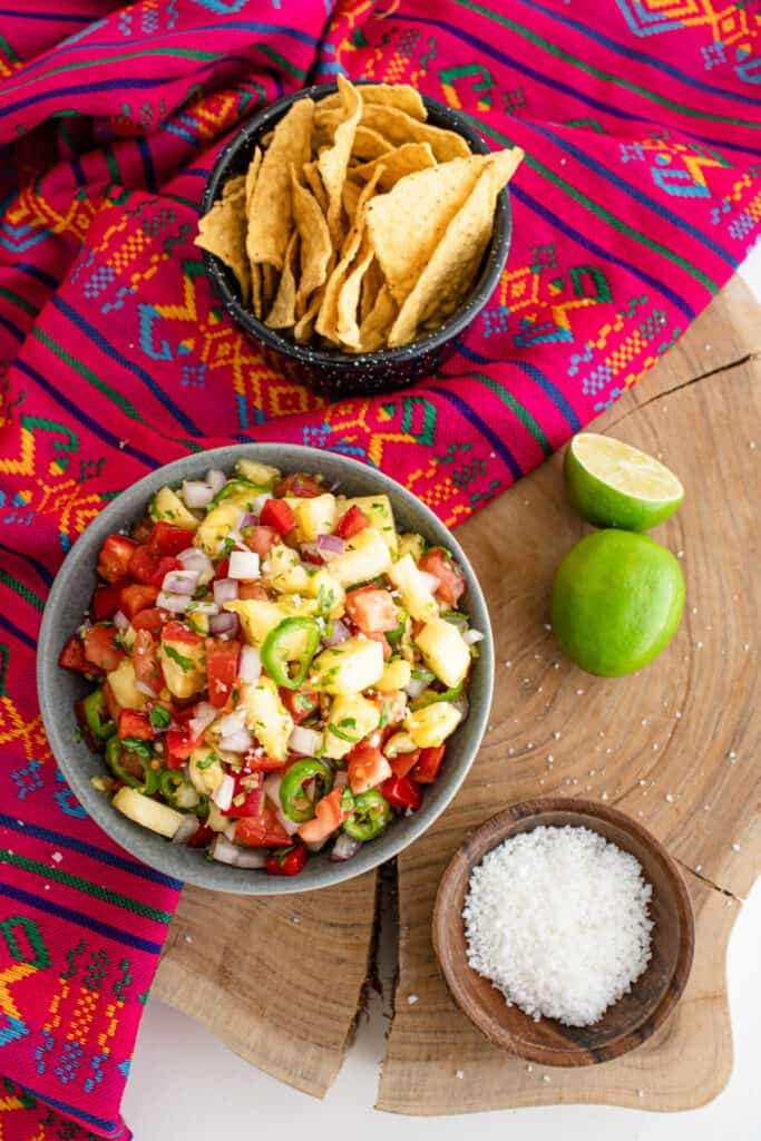 fresh pineapple salsa on a wooden board with fresh limes
