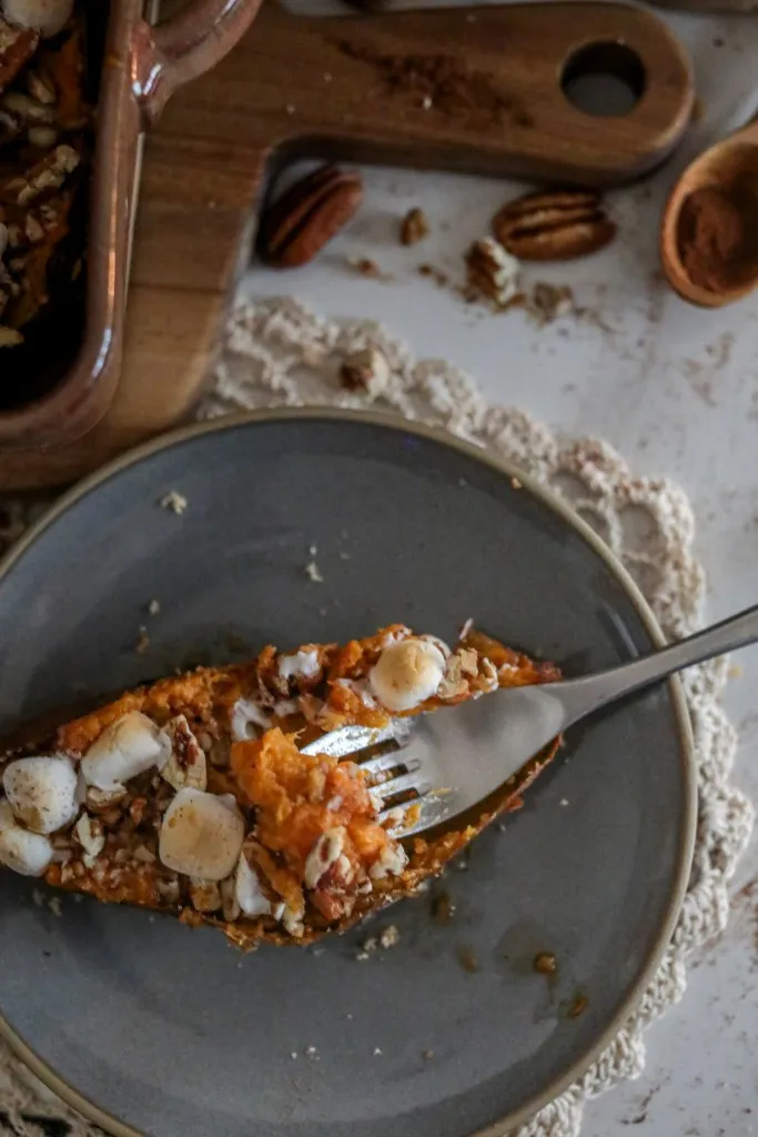 a fork in a twice baked sweet potatoes recipe on a grey plate