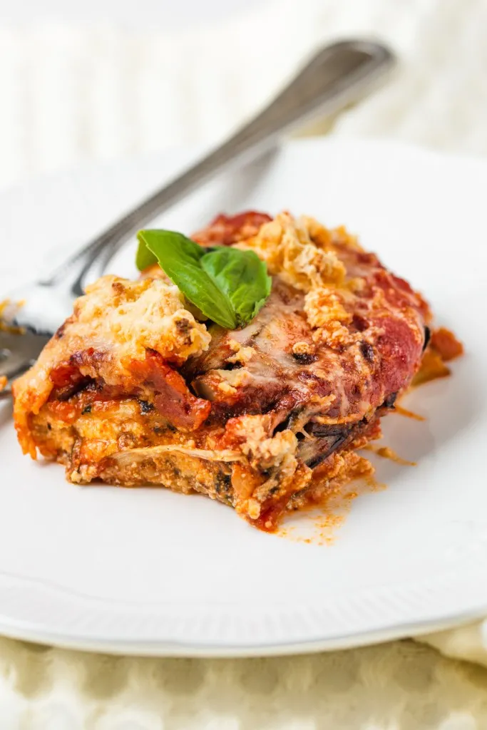 fresh made vegetable lasagna with fresh basil on a white plate