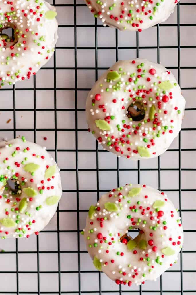 cream cheese glazed doughnuts with christmas sprinkles on a cooling rack