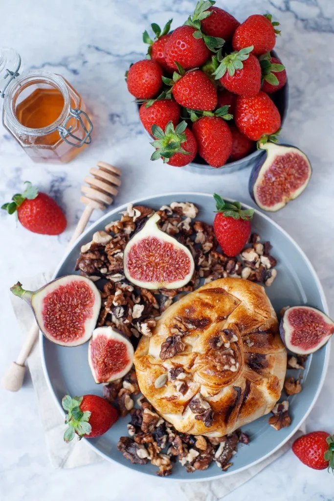 overhead shot of baked brie in a fresh puff pastry with candied walnuts and sliced figs