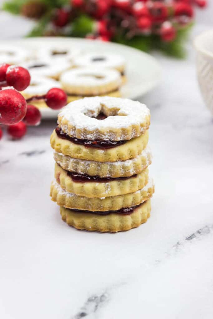 stack of christmas linzer cookies on a decorative plate