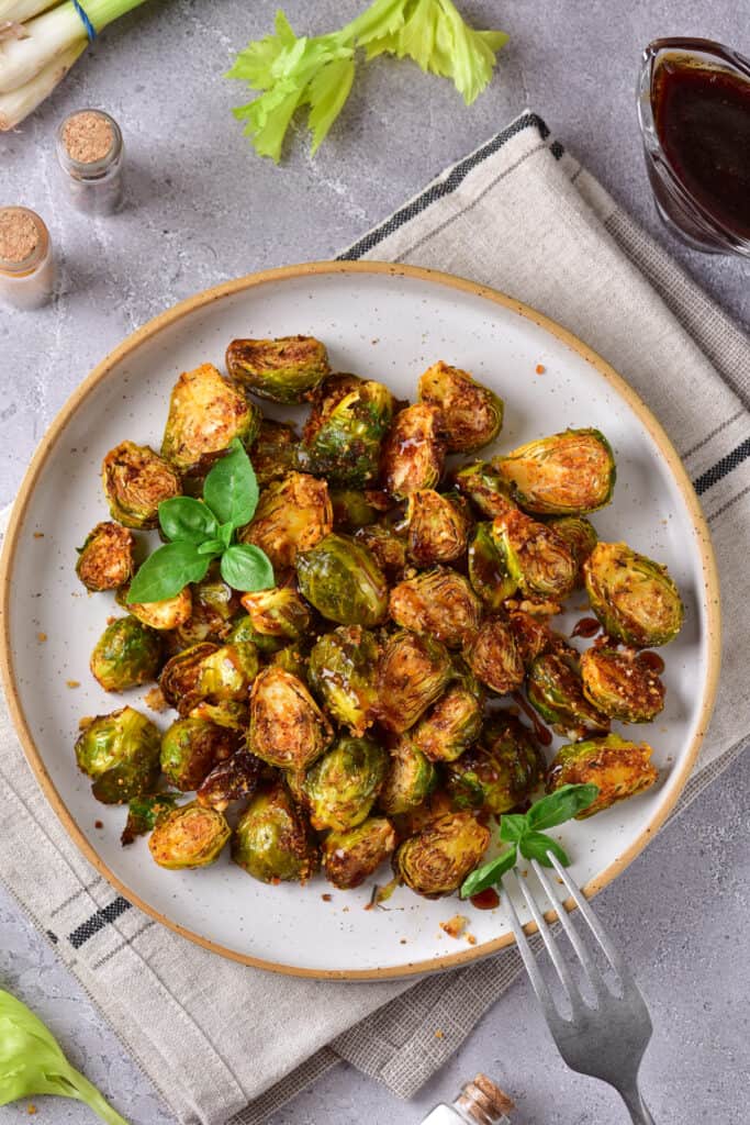 overhead shot of air fryer brussels sprouts on stone colored plate with tan brim and a fork