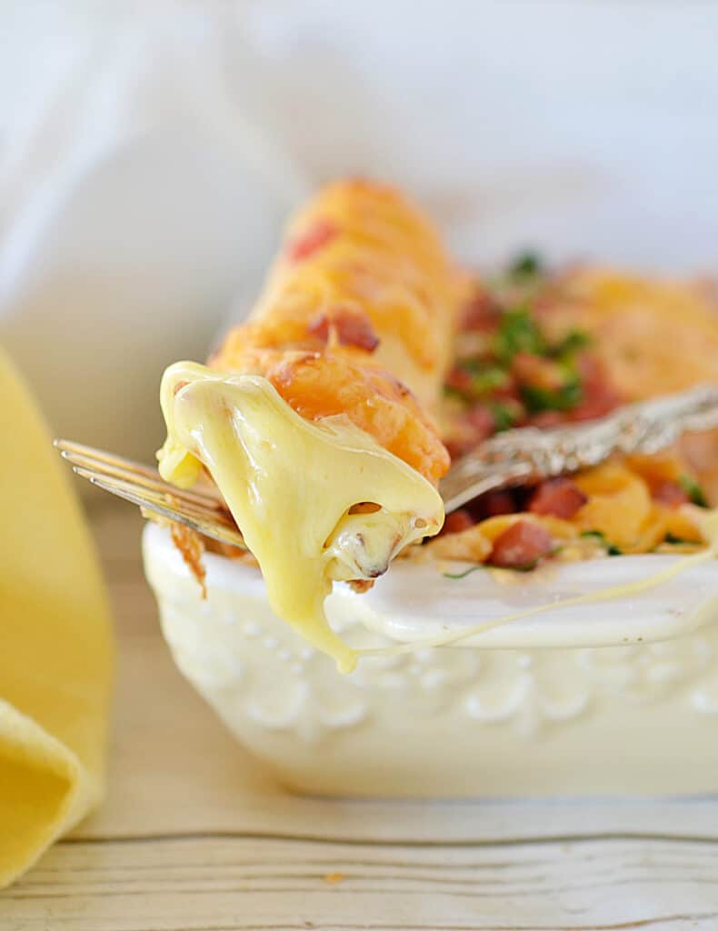 a close up side view shot of a breakfast enchiladas in a white casserole baking dish