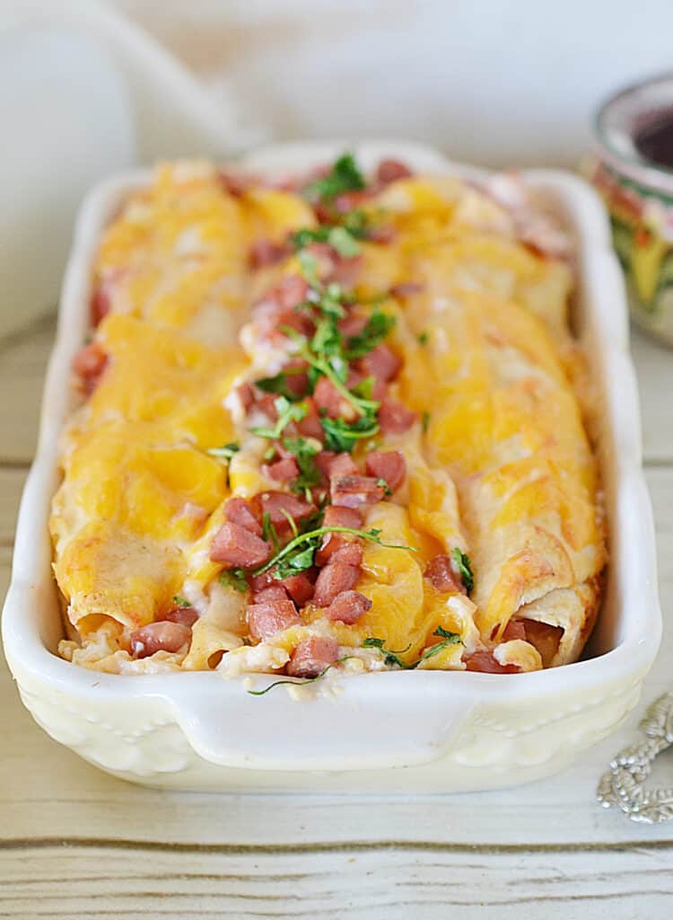 close up view of breakfast casserole enchiladas with crumbled bacon and parsley on top