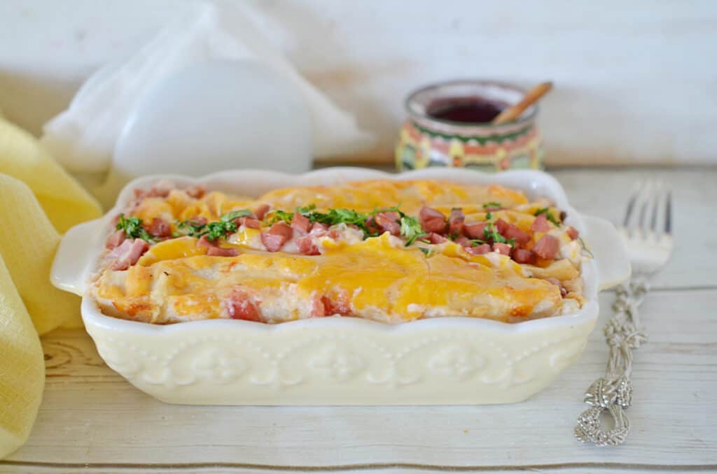 breakfast casserole with ham, bacon and parsley in the middle covered with cheese