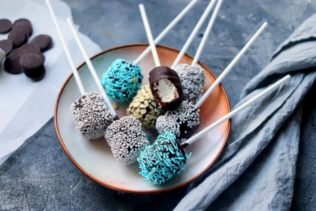 overhead shot of chocolate and sprinkled covered christmas snowballs on a stick