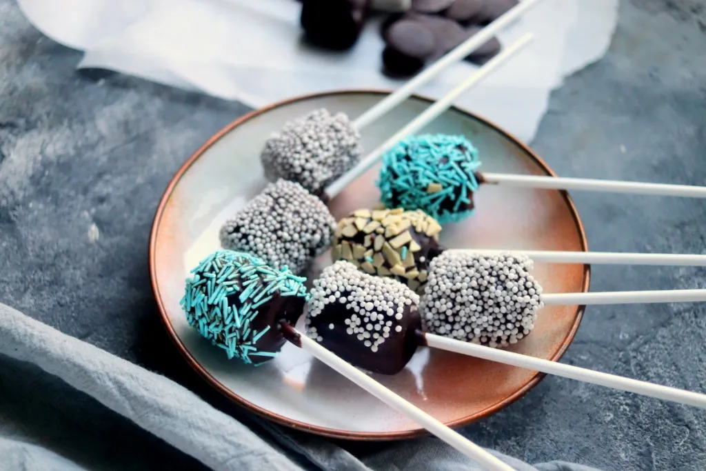 a plate of blue and white sprinkled chocolate covered marshmallows