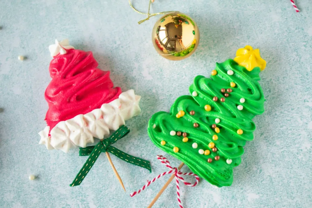 overhead shot of christmas meringue pops on a blue speckled background. 