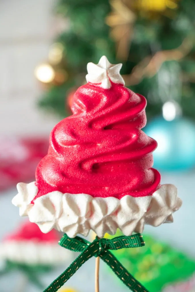 santa claus hat meringue dessert on a stick with a green ribbon