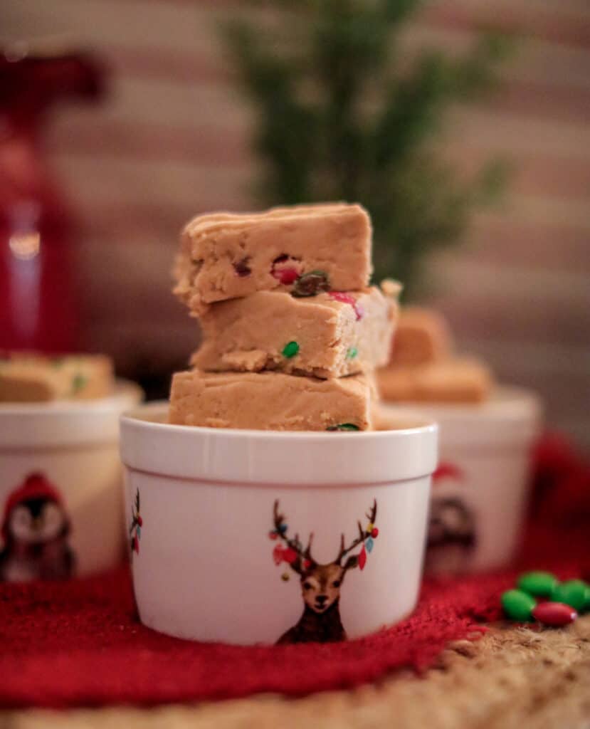 side view shot of stacked christmas peanut butter fudge in a reindeer decorated white ceramic dish