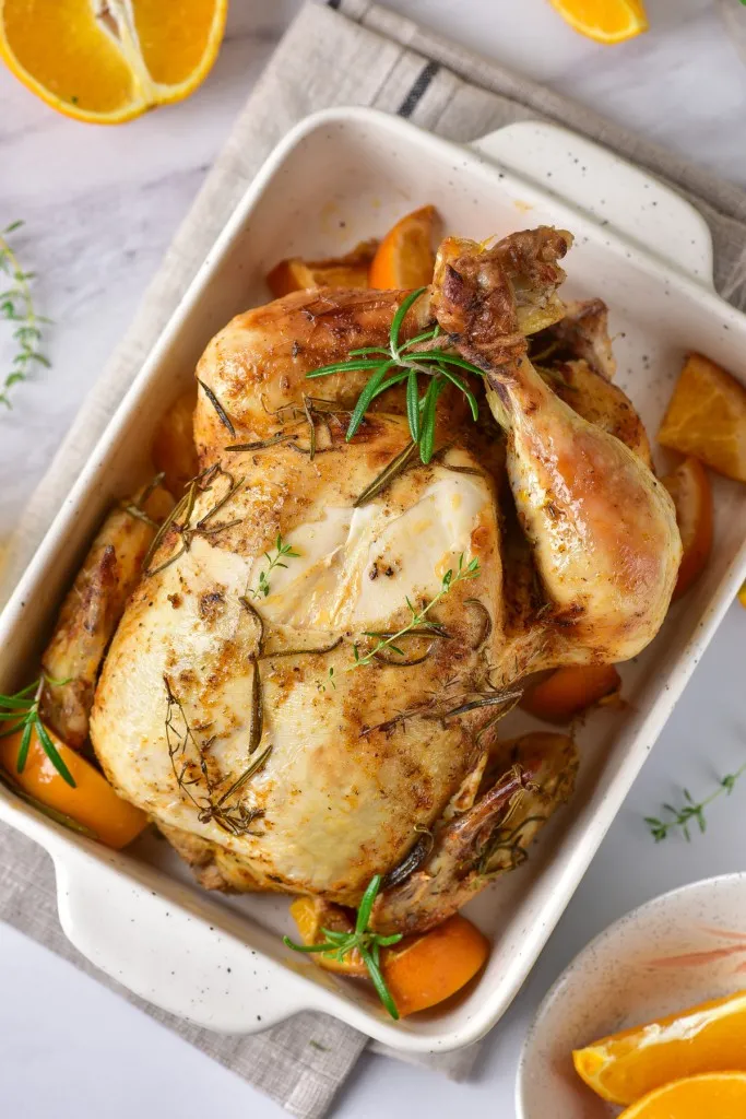 overhead shot of dutch oven orange roasted chicken in a white dish