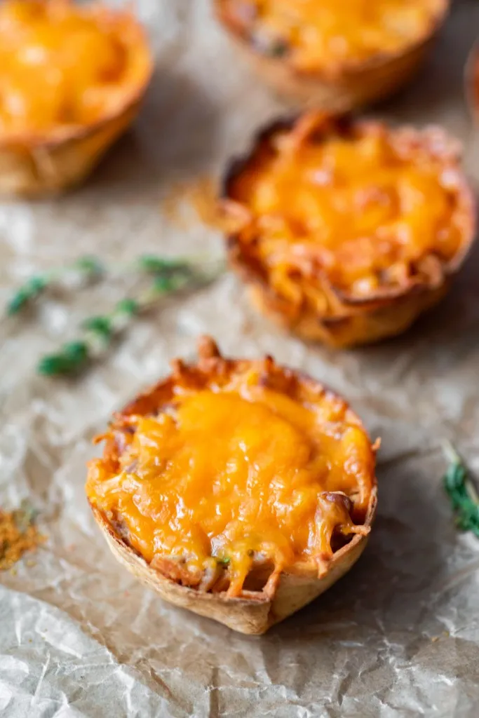 overhead view mini mexican pizzas on parchment paper with a bowl of salsa with red peppers and tomatoes in background