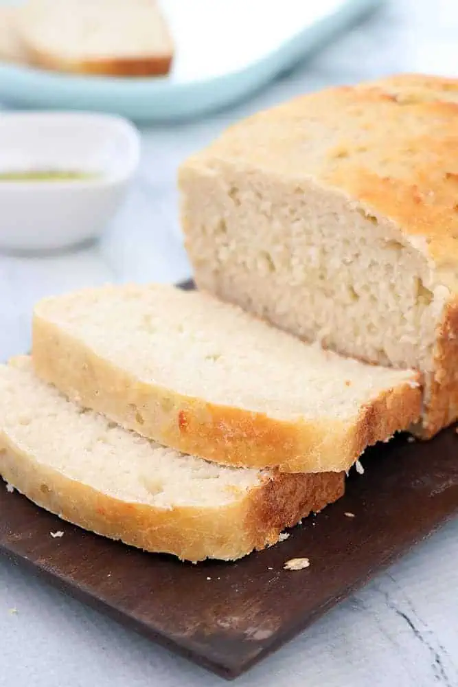 side view of fresh home made slow cooker 2 ingredient bread on a brown board with a dish of olive oil in the background