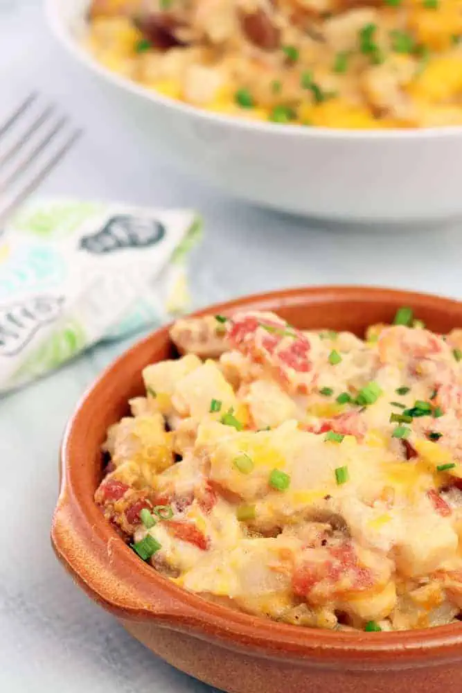 side view of slow cooker cheesy potatoes with sausage and diced chives