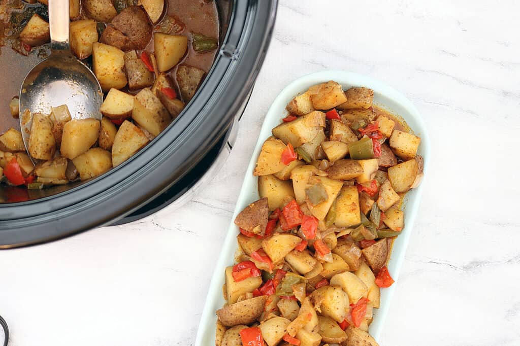 slow cooker country style potatoes on a blue plate next to a crockpot