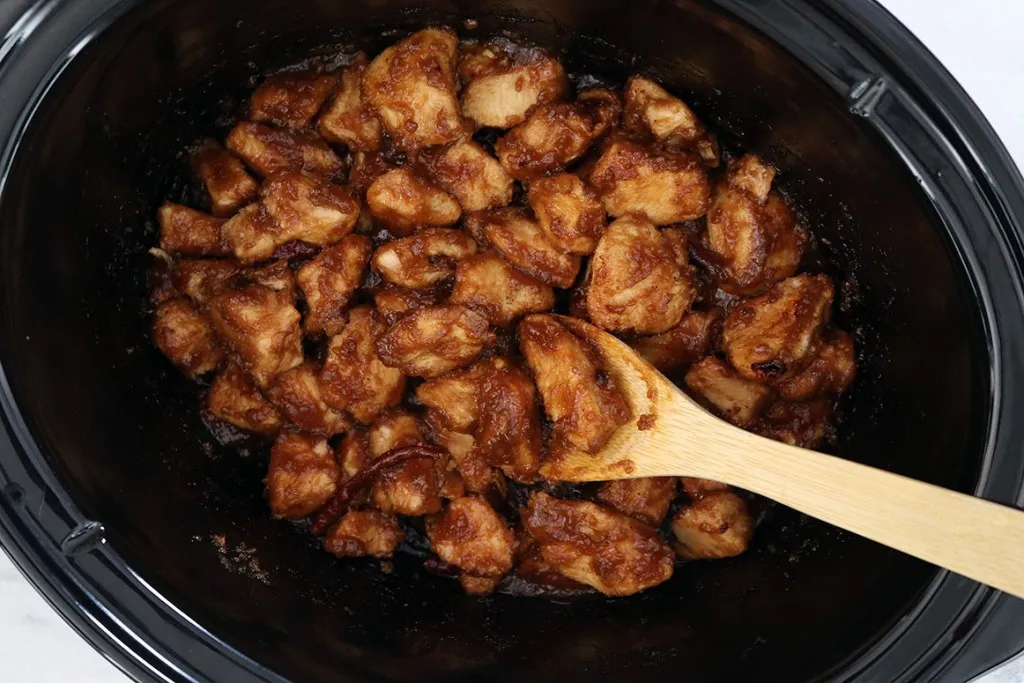 general tso's chicken in slow cooker and wooden spoon