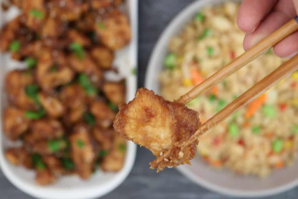 chopsticks holding a piece of slow cooker general tso's chicken