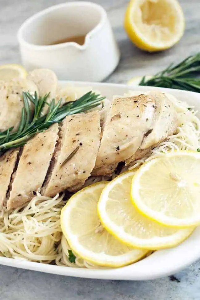 slow cooker lemon chicken with sliced lemons over angel hair pasta