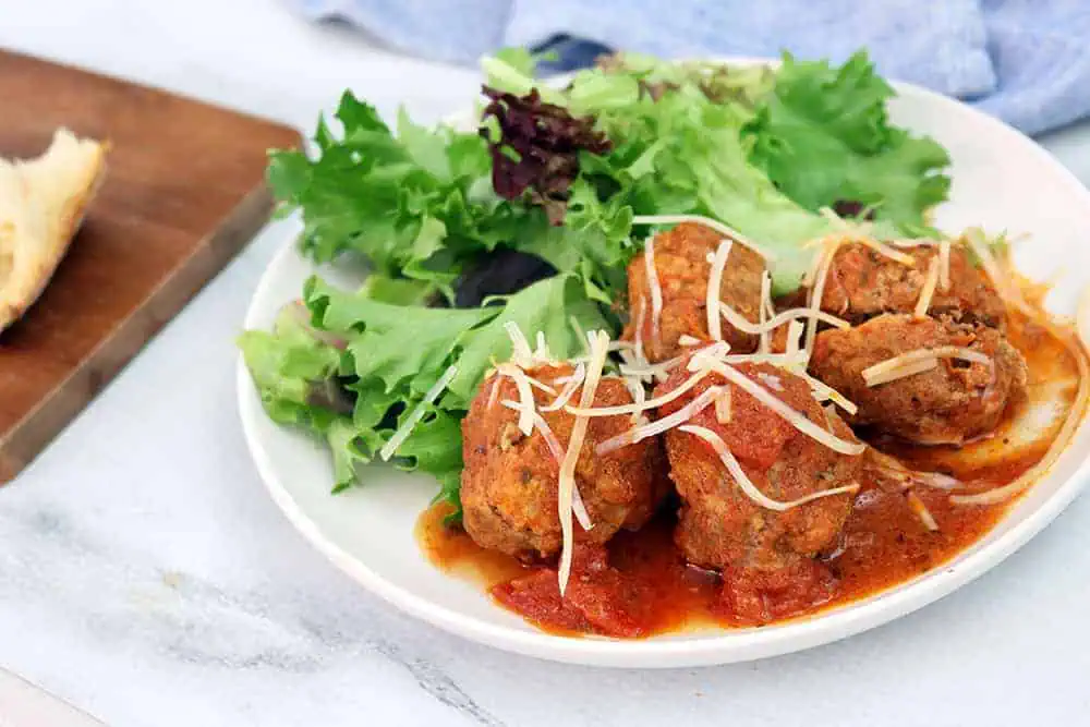 close up view of slow cooker meatballs and mixed greens salad