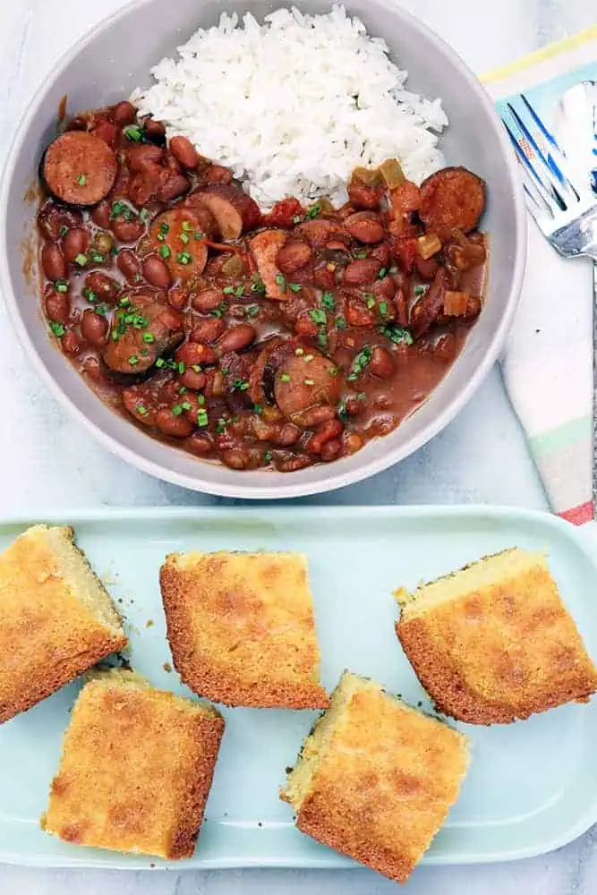 a bread of cornbread next to a bowl of red beans and rice