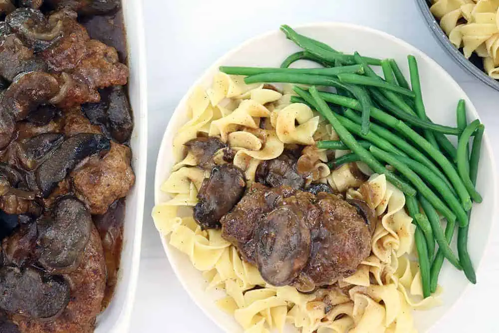homemade hamburger steaks with mushrooms over egg noodles with green beans