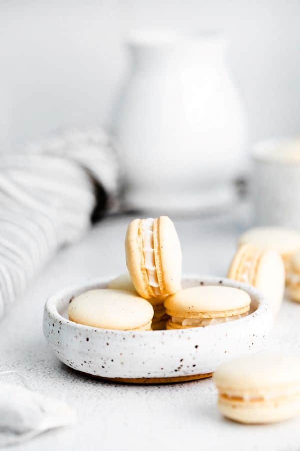 a beautiful and airy photo of earl grey macarons with a creamy filling in a flat bowl