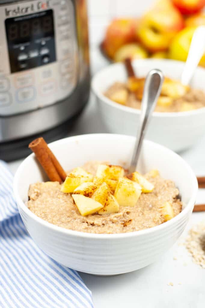 a white bowl full of apple cinnamon oatmeal made in the instant pot