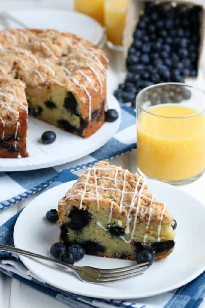 easy to make blueberry crumb coffee cake on a white plate and fresh bluberries