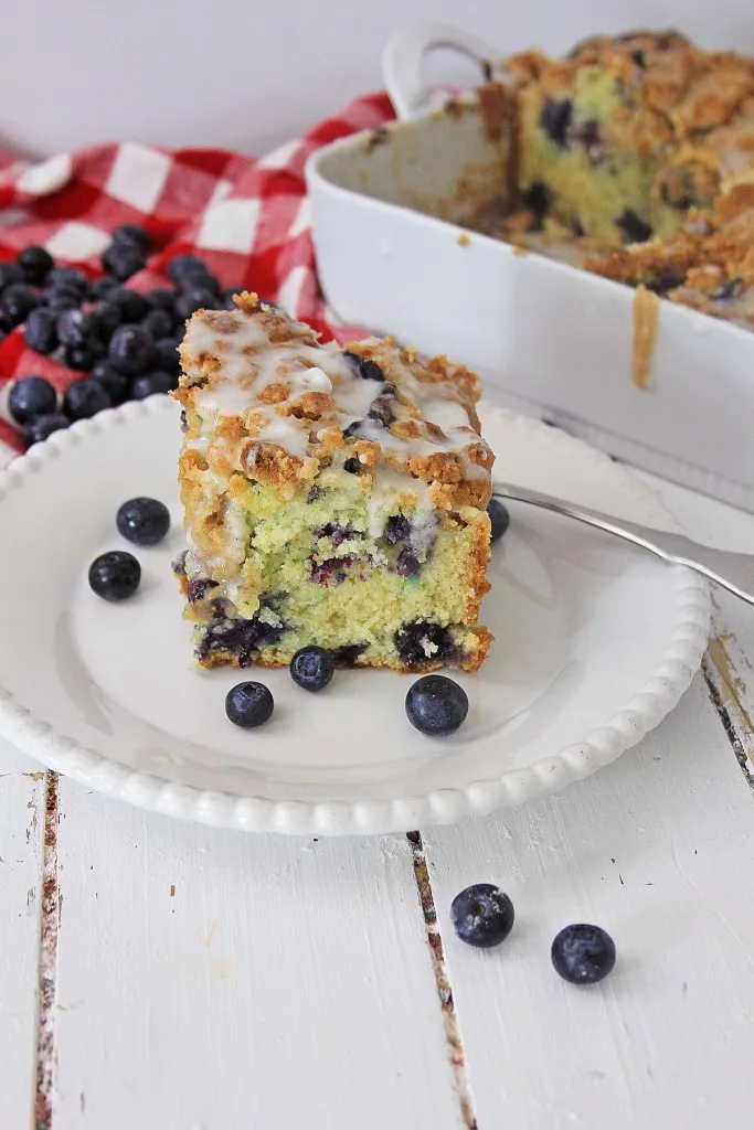 blueberry coffee cake on a white plate and a drizzle of icing