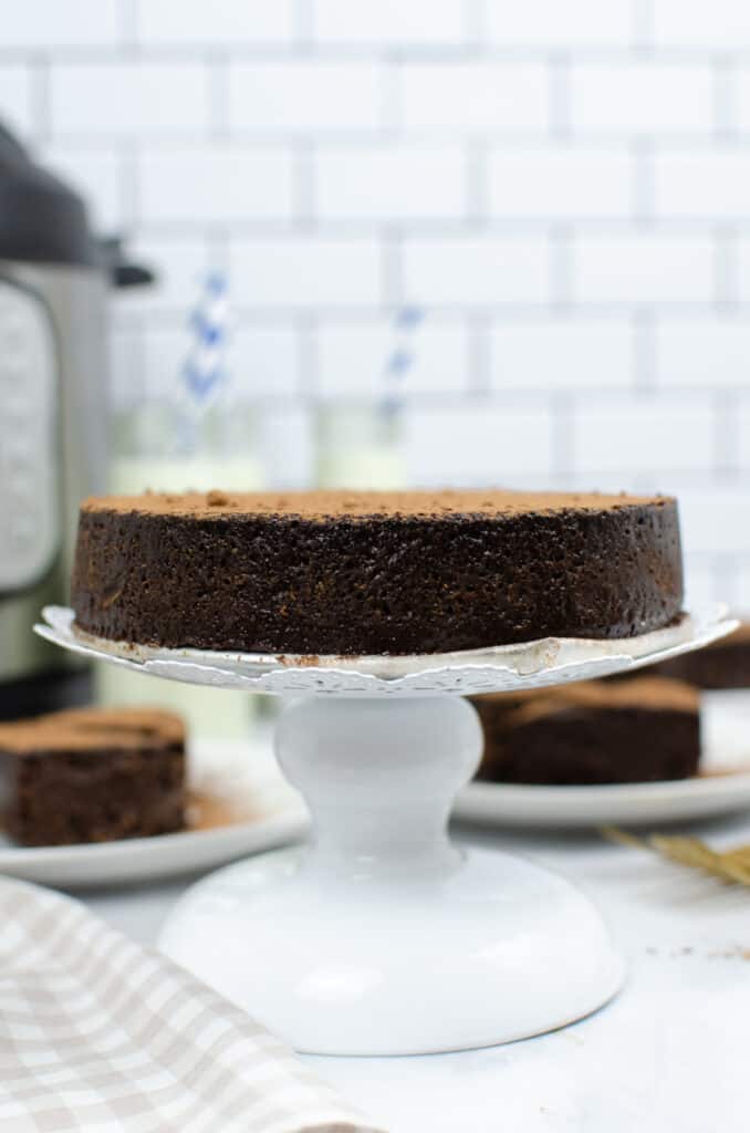 a flourless chocolate cake on a white cake platter made in the instant pot
