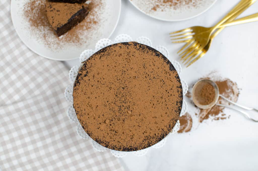 another view overhead of an instant pot flourless chocolate cake dusted cocoa on a ceramic cake platter