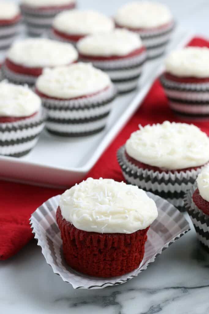 red velvet cupcakes in black and white striped paper liners on a red napkin